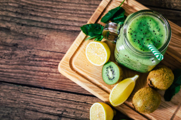 Fototapeta na wymiar Delicious kiwi smoothie with mint in mason jar on table against dark wooden background. Healthy lifestyle concept. Top view
