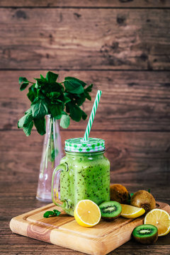 Delicious kiwi smoothie with mint in mason jar on table against dark wooden background. Healthy lifestyle concept