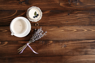 Obraz na płótnie Canvas A cup of fragrant cappuccino, blueberry cake and a branch of lavender on a wooden background. Diamond engagement ring on the wooden stand.jpg