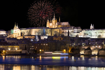 Fototapeta na wymiar Fireworks above night colorful snowy Prague gothic Castle with Charles Bridge, Czech republic