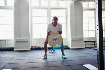 Mature man in sportswear weightlifting alone in a gym