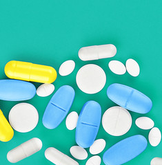 Assorted pharmaceutical medicine pills, tablets and capsules on green background