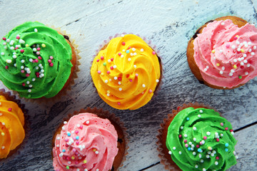 Tasty cupcakes on wooden background. Birthday cupcake in rainbow colors