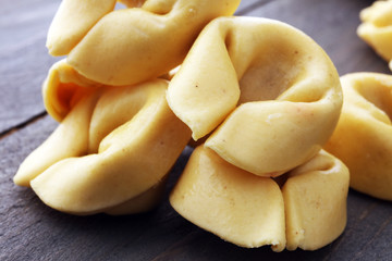 Raw cheese filled tortellini pasta on wooden background