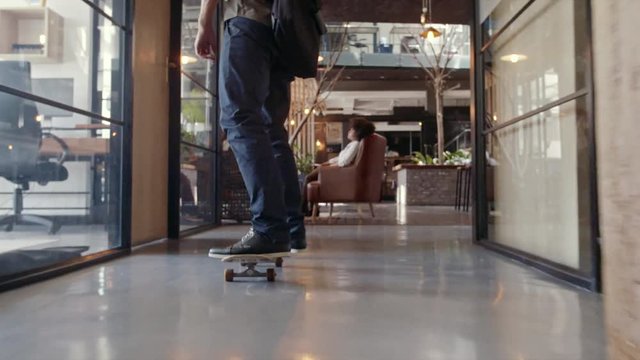 Creative professional skateboarding in office. Casual businessman skating through his startup office.
