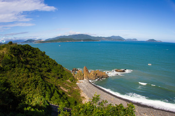 Sea view panorama. Small rocks near the shore, waves and white clouds on a blue sky. Vietnam seascape near Nha Trang city.