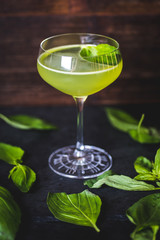 A sheet of mint floats in a green cocktail.