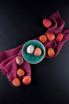 ripe, vermilion exotic lichees decorated on a slate plate kitchen table background with napkin