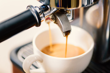 Coffee making, hot coffee flowing into a cup from espresso machine