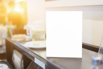Mock up Menu frame on Table in Bar restaurant or coffee shop ,Stand for booklets with white sheets of paper acrylic tent card on cafeteria ,barista preparing cup of coffee for customer in background.