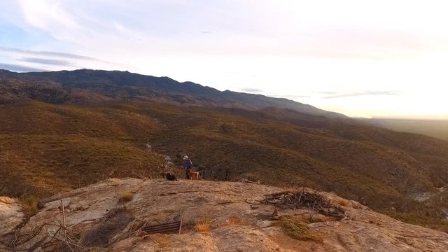 Aerial flyover of a mature man hiking and drinking water in the desert