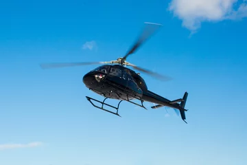 Fototapeten Solo schwarzer Hubschrauber in blauem Himmel © PhotoSpirit