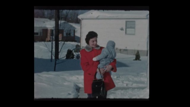 1960 Mom holds baby bundled up baby boy after snowstorm