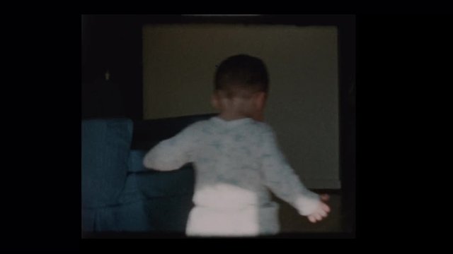 1960 Cute little boy wanders around living room