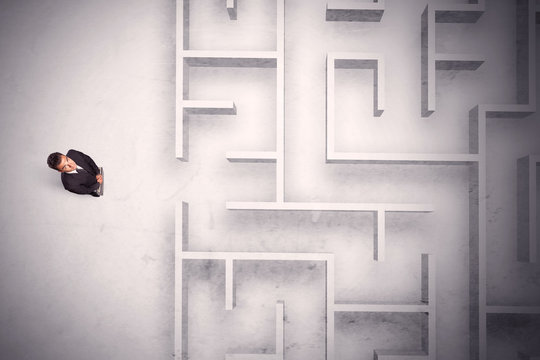 Confused businessman standing at a maze wall