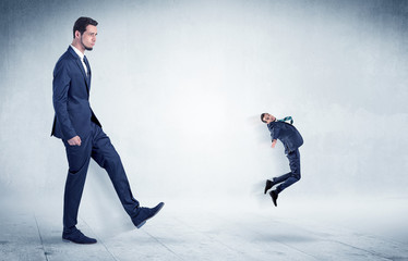 Big businessman kicking small businessman