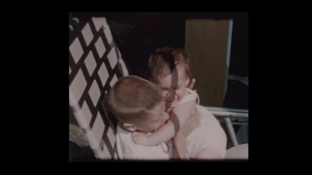 1960 7 year old boy holding baby brother in lawn chair
