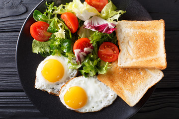 Fototapeta na wymiar Organic food breakfast: fried eggs with fresh vegetable salad and toast close-up on a plate. horizontal top view