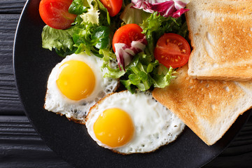 healthy breakfast of fried eggs with fresh vegetable salad and toast close-up. horizontal top view