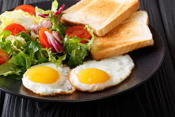 fried eggs with fresh vegetable salad and toast close-up. horizontal