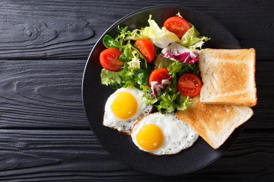 hearty breakfast: fried eggs with fresh vegetable salad and toast close-up. horizontal top view