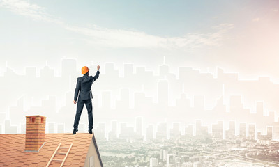 Man architect draw silhouette of modern city on blue sky. Mixed 