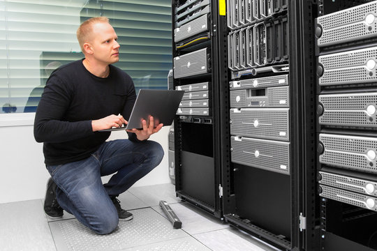 Consultant Using Laptop While Monitoring Servers In Datacenter