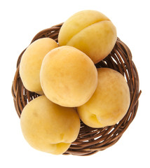 apricot in wicker basket isolated on white background