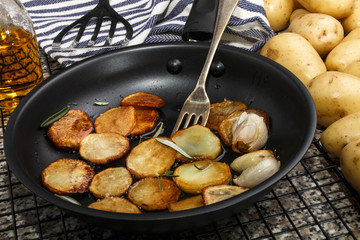 roasted potato slices with garlic and olive oil in a pan