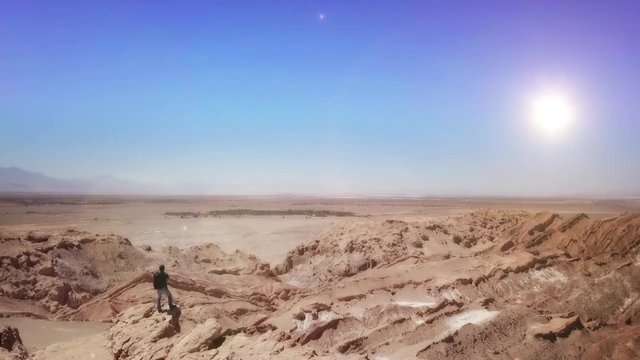 Aerial shot of male trekker standing at the cliff contemplating the horizon of the Atacama desert. 4k