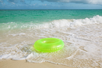 Fototapeta na wymiar floating ring on sandy beach with waves