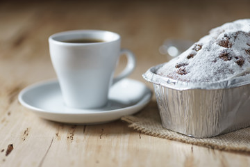 Coffee cup and cake with raisins on wooden desk