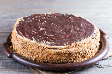 Sweet home layered honey cake on a wooden table with with chocolate icing