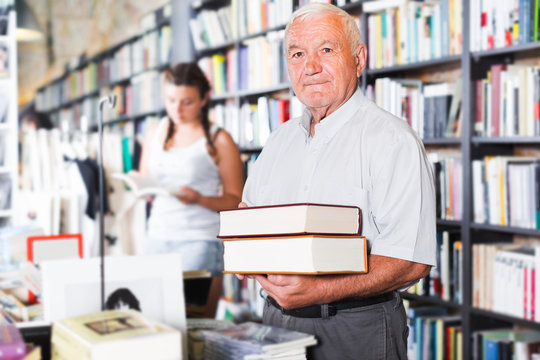 Old male is showing book that he bought