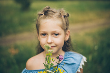 young girl smalling field flowers