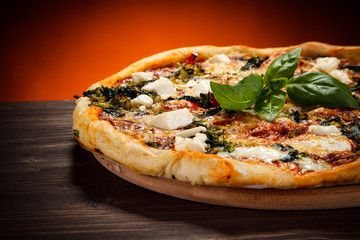 Pizza with feta cheese and spinach on wooden table