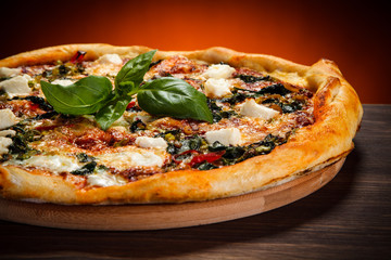 Pizza with feta cheese and spinach on wooden table