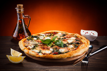 Pizza with feta cheese and spinach on wooden table