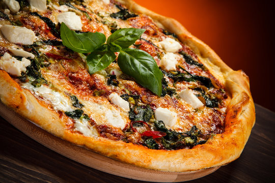 Pizza with feta cheese and spinach on wooden table