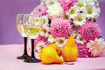 Two elegant glasses of white fruit wine or champagne and ripe yellow pears on the table with...