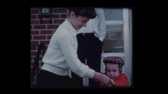 1960 Young girl helps little boy down the steps
