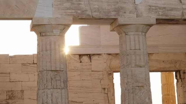 sun setting behind the propylaea at the acropolis in athens, greece