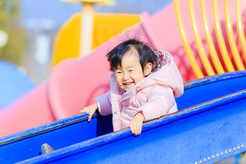 Fototapeta na wymiar 公園の滑り台で遊ぶかわいい子供