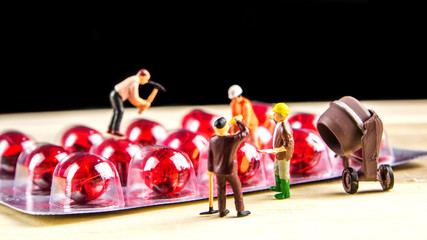 Fototapeta na wymiar teamwork of miniature figurines with bunch of red pills