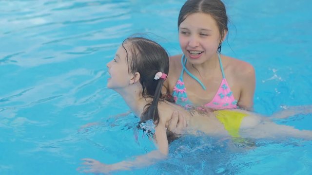 Girl teaches her younger sister to swim