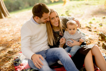 Young family sitting on the ground in autumn park