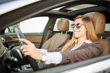 Beautiful businesswoman driving car while smiling