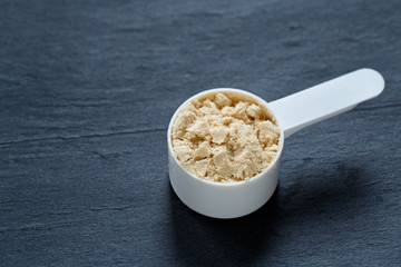 Scoop filled with protein powder against slate background