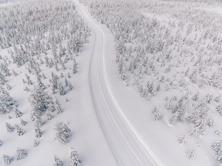 Aerial view of the road in the winter snow forest in Finland