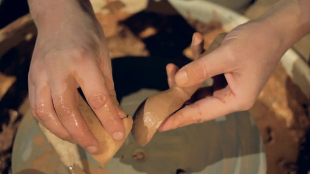 A potter covers a clay spoon with water. 